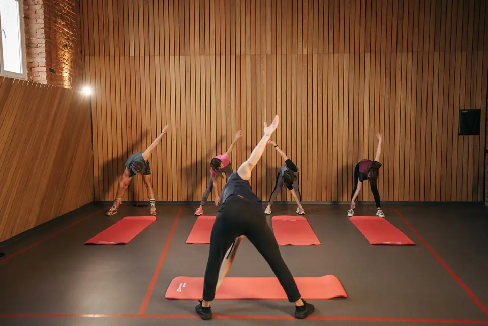 A yoga class stretching on mats in a wooden studio